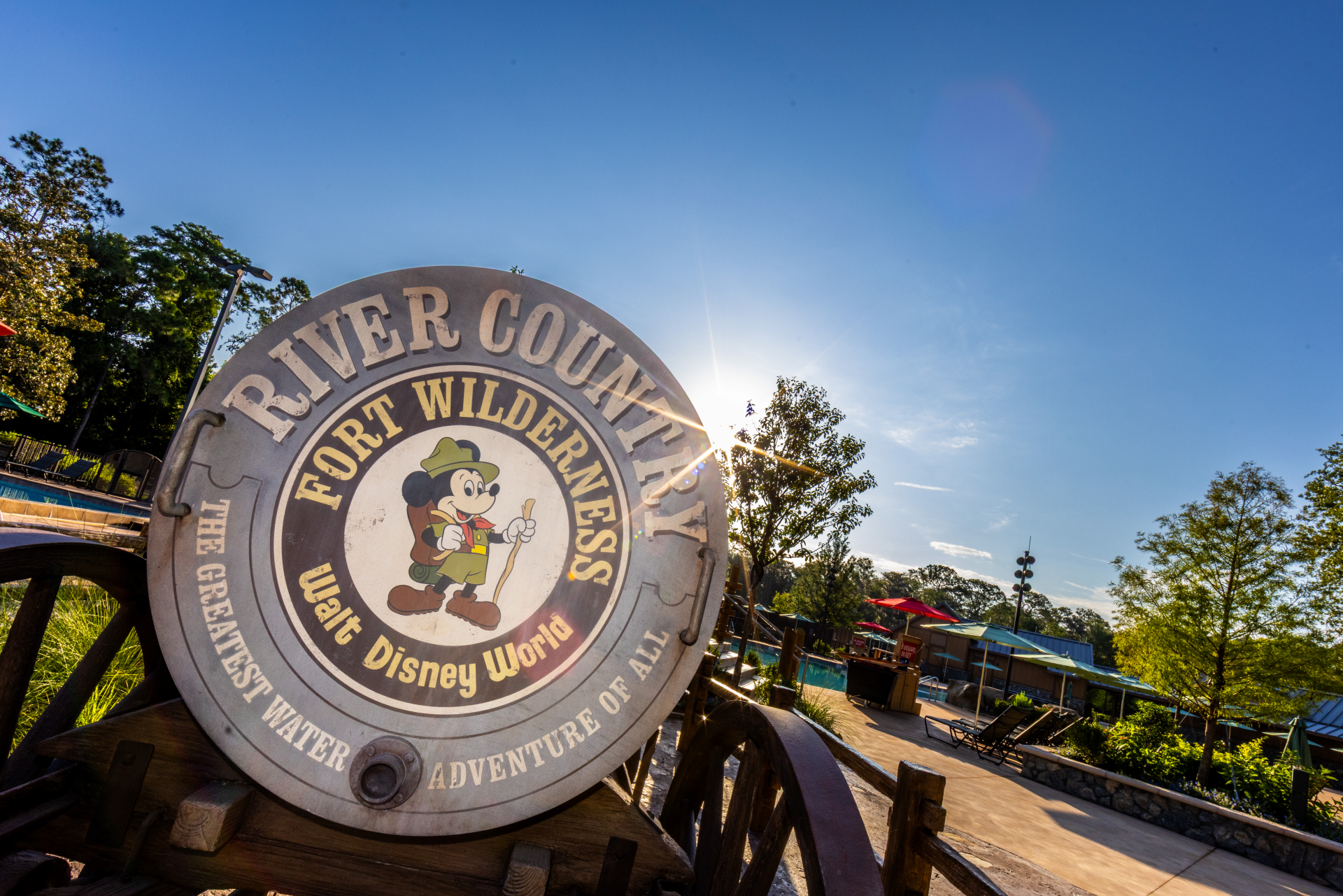 A weathered metal barrel on a wooden wagon painted with the River Country logo, showing Mickey Mouse in camping gear and the words The Greatest Water Adventure of All