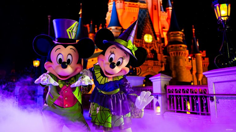 Mickey Mouse and Minnie Mouse pose in their Halloween costumes in front of Cinderella Castle at Magic Kingdom.