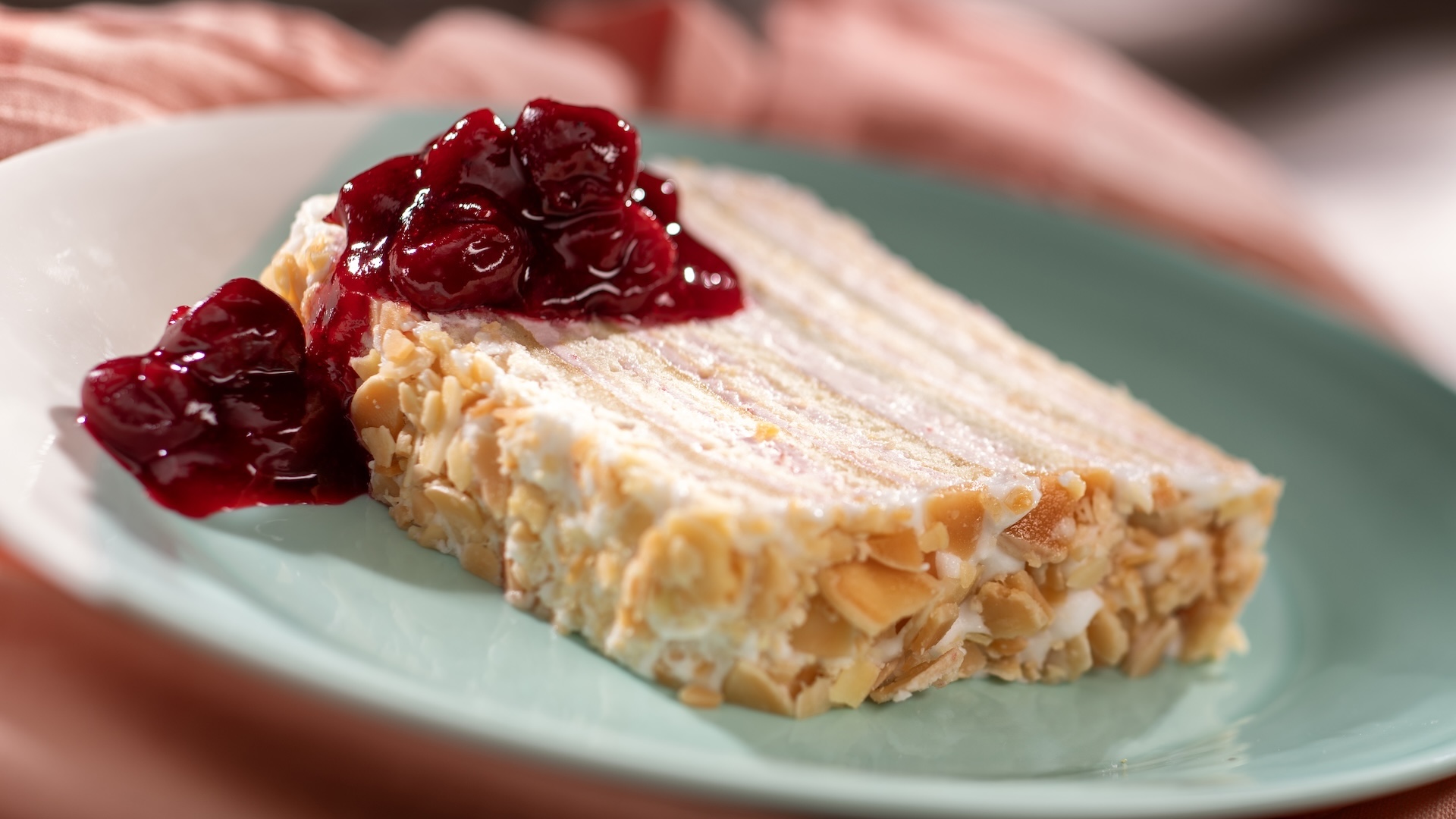 Kirschwasser Torte with cherry-brandy buttercream, fondant, sugared almonds, and cherry compote on a wooden board.