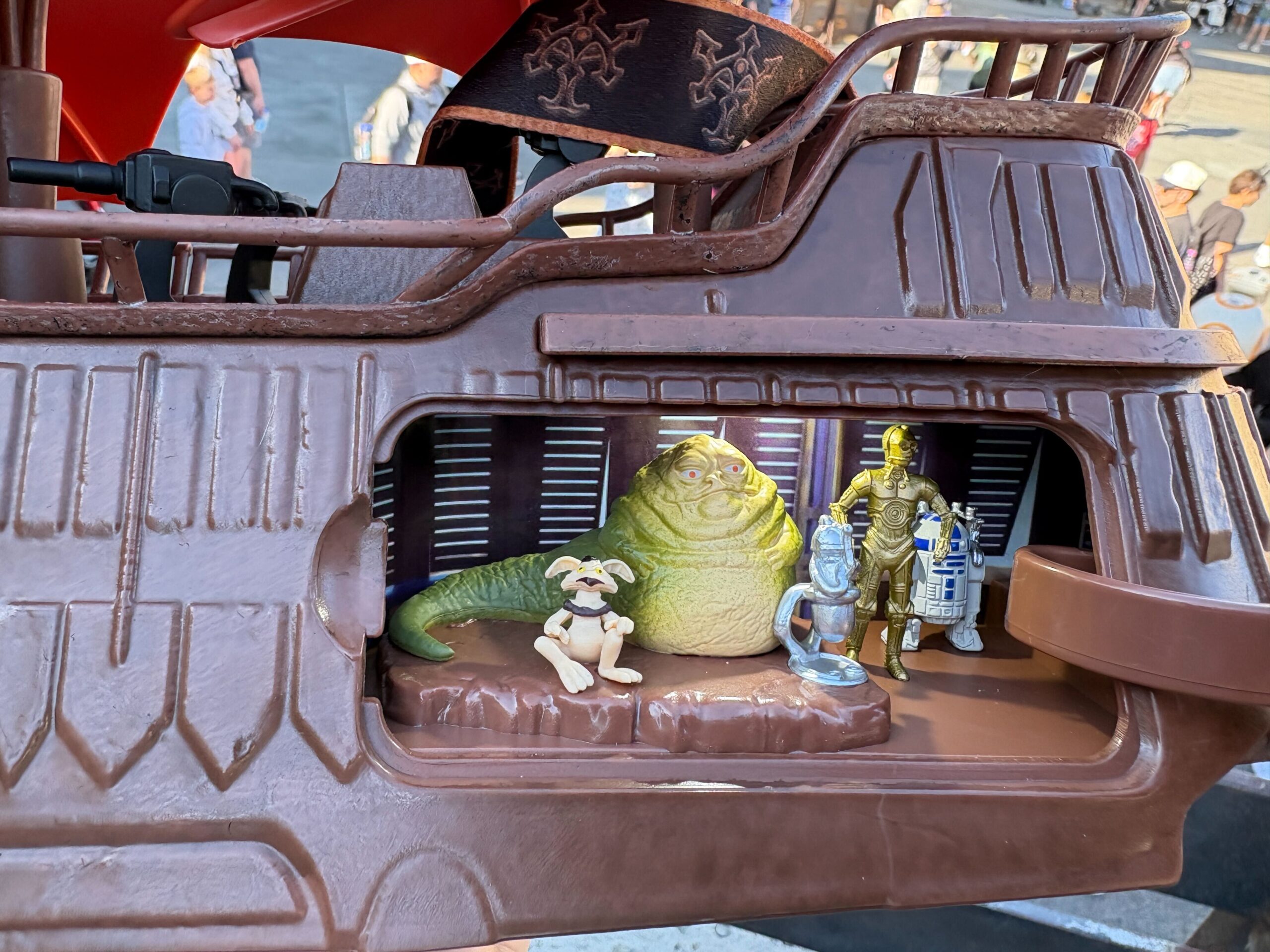 The lit-up interior of the Jabba's Sail Barge bucket revealing Jabba, Salacious B. Crumb, C-3PO, and R2-D2 inside.
