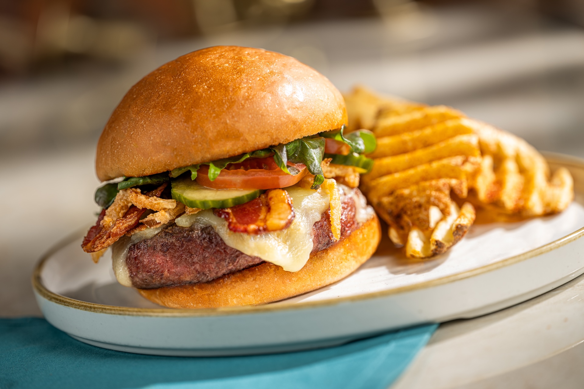 The Turf Club Burger with bacon, white cheddar, onion straws and pickles, served with waffle fries