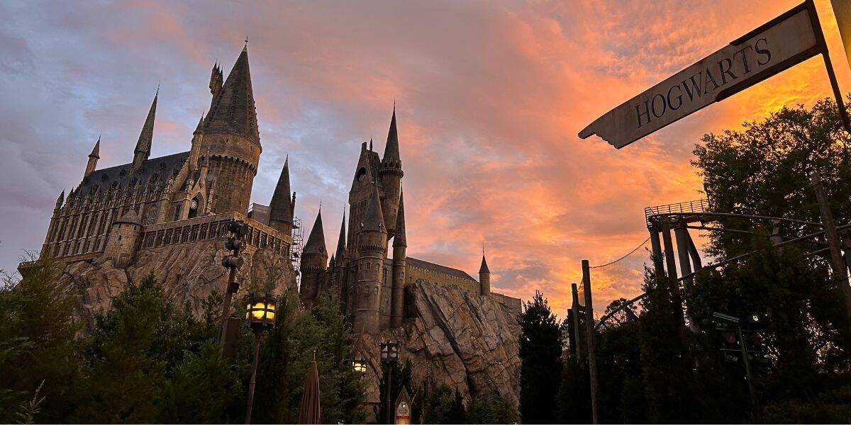Hogwarts Castle silhouetted against a warm sunset sky at Universal Orlando.